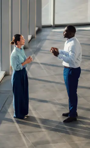 Homem e mulher conversam em corredor de um ambiente corportativo