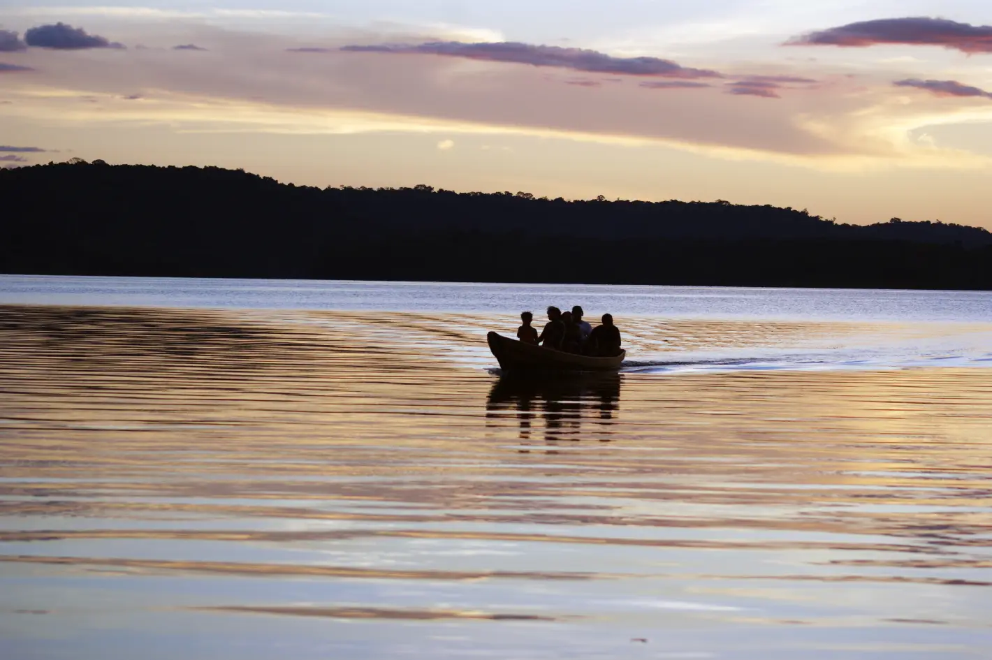 Embarcação com quatro pessoas navega em rio no Amazonas