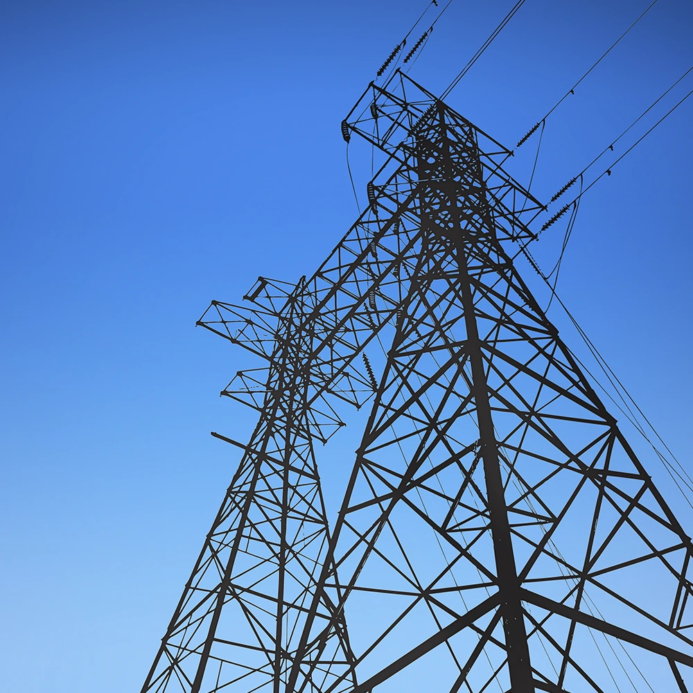Torres de transmissão de energia elétrica com cabos de alta tensão vistas de baixo, destacadas contra um céu azul sem nuvens.
