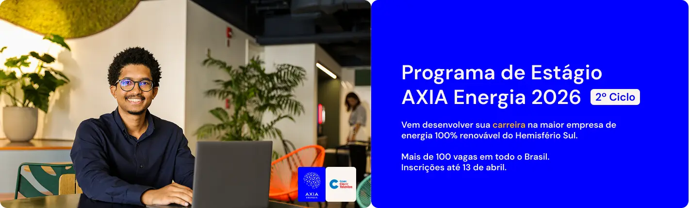 Rapaz negro de óculos e camisa azul trabalha no computador e sorri